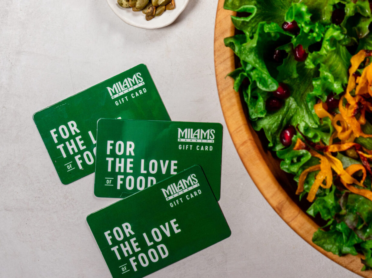 Three green milam's markets gift cards laying next to a green salad