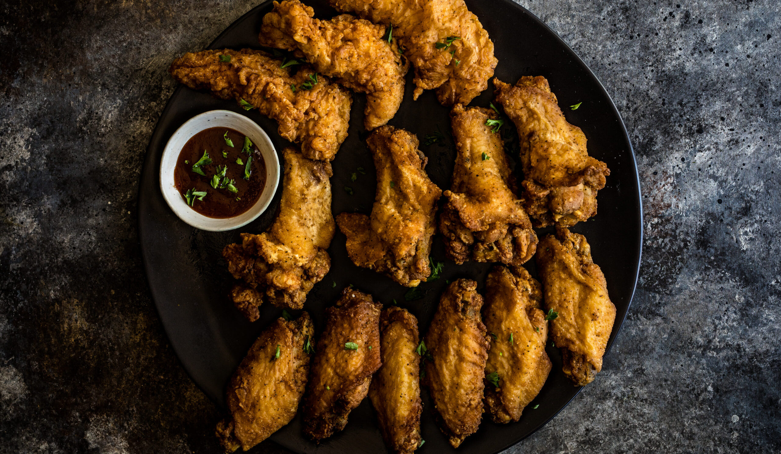 a plate of fried chicken wings on grey counter