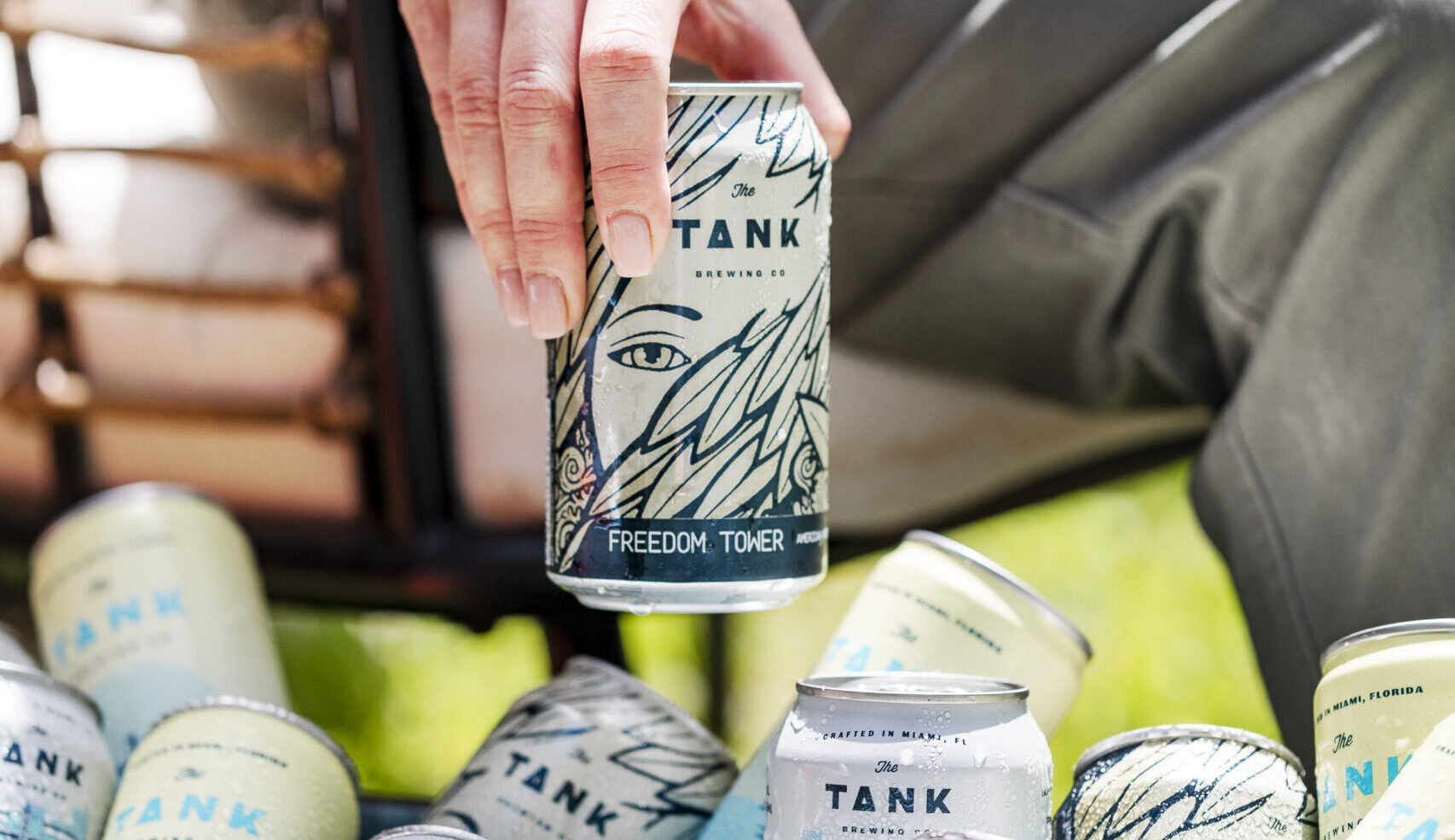 Tank Brewing Co Freedom tower beer being held above a cooler of more Tank Brewing Co. beers