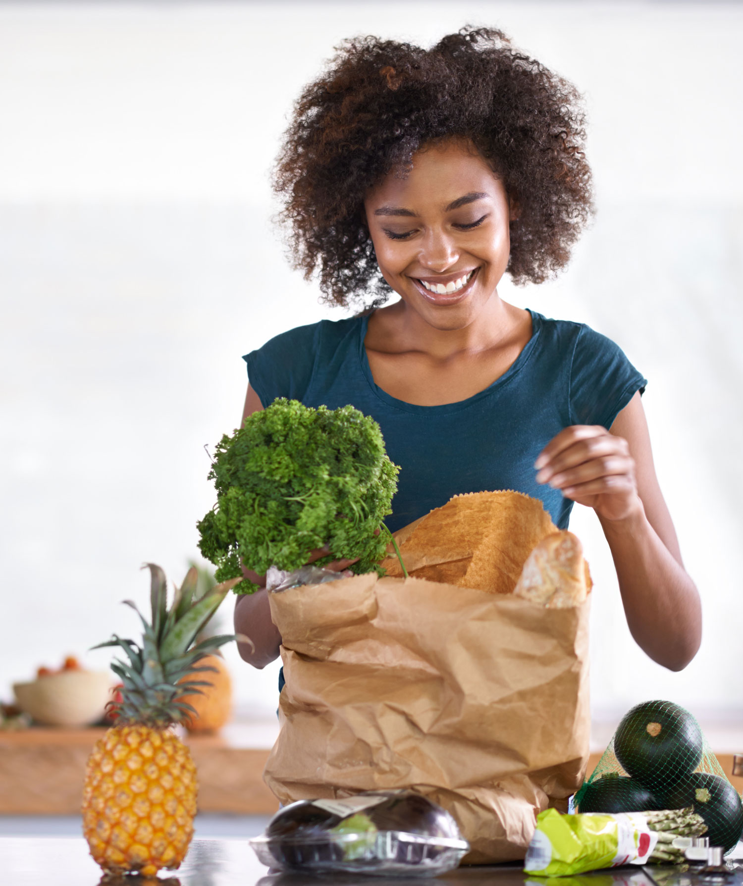 smiling woman unpacking grocery bag on counter